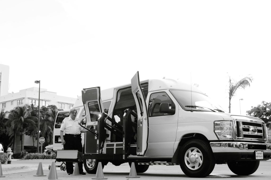 A black and white image depicting an accessible transport van with a lift, enhancing mobility for passengers with disabilities.